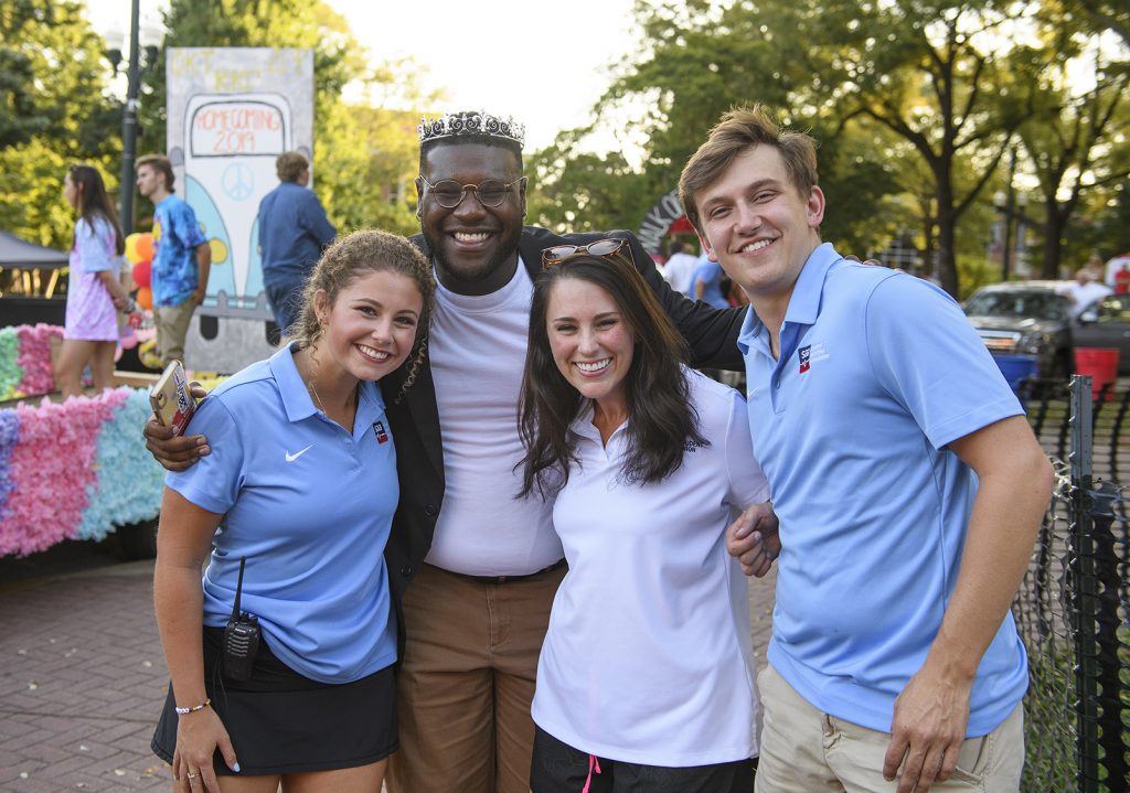 Carl Tart smiles while having his picture taken with a group of UM students.