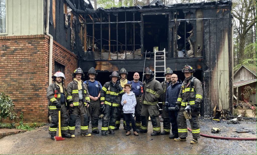 Group of firefighters in front of a burnt place