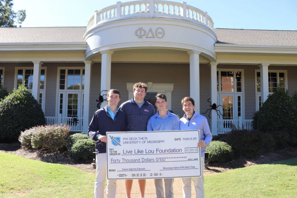 Holding a big check in front of Phi Delta Theta