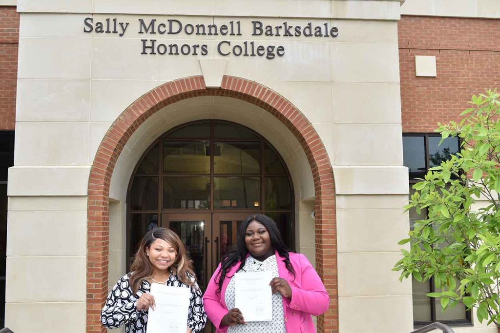Jazmin King and Zuri Dixon-Omere in front of Honor's College with their thesis