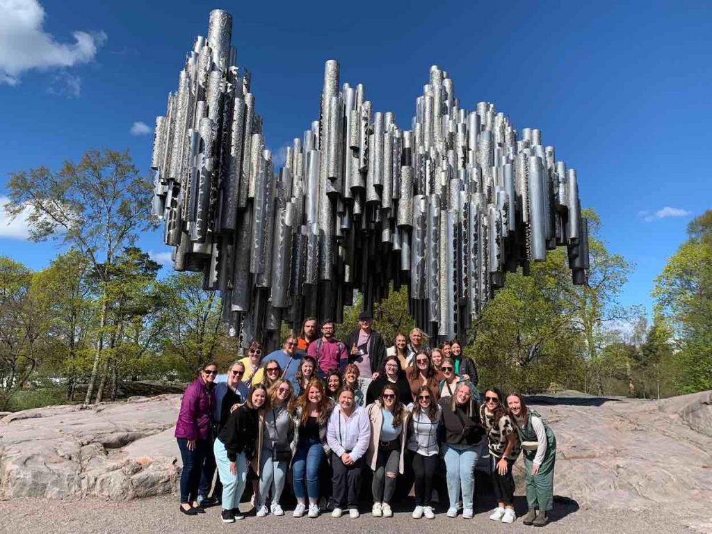 Raegan poses with a group of classmates in front of a sculpture during a study abroad trip.