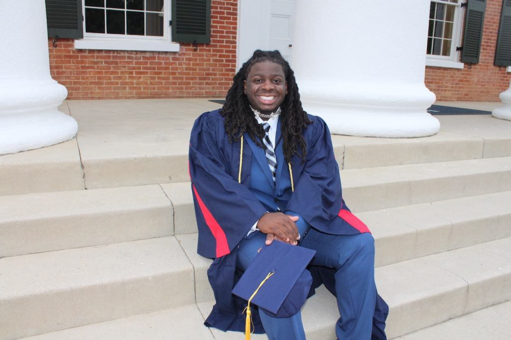 Thomas Riddle poses on the steps of the Lyceum in his graduation cap and gown.