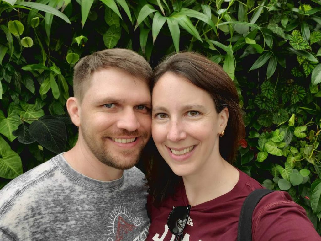 Jamie and Holli in Orlando, Florida. They are standing in front of lots of greenery.