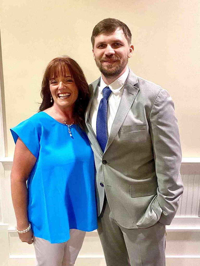 Brown wears a blue shirt next to Cox wearing a tan suit.