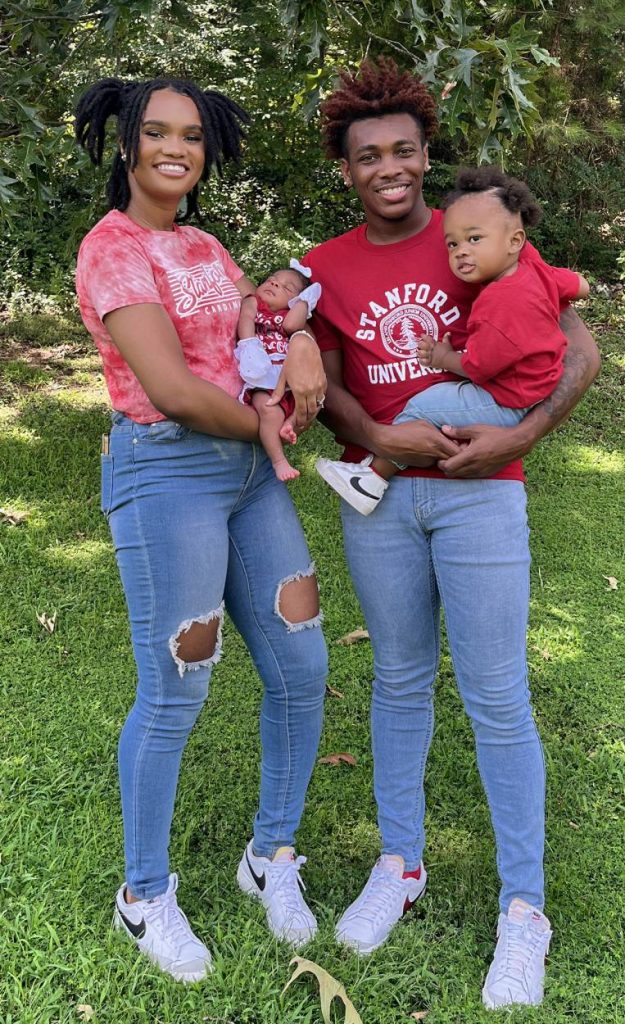 Cellas and his wife wear jeans and red t-shirts as they hold their two children.