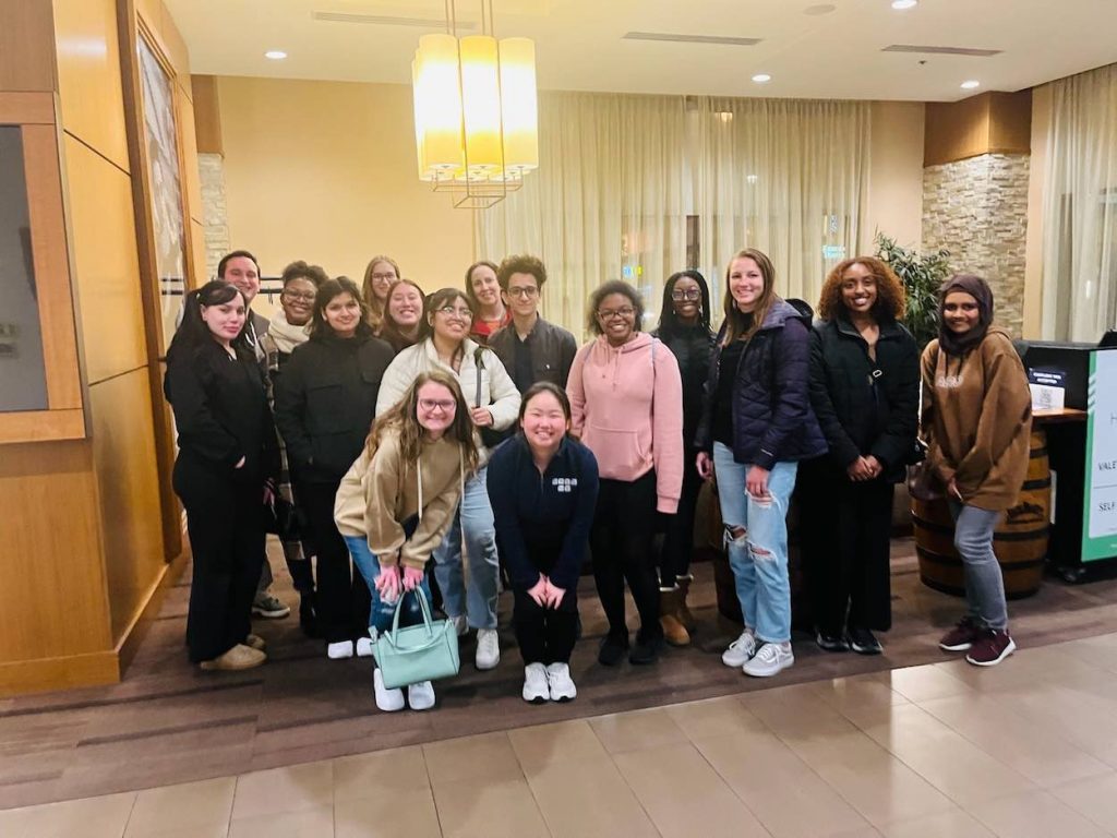 Suh stands in a hotel lobby with a large group of other students. 