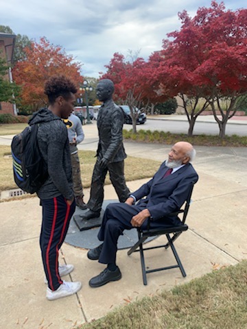 Cellas stands talking to James Meredith, who is sitting. They are next to the James Meredith monument.