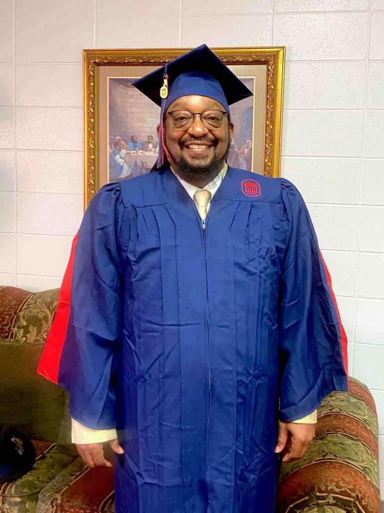 Leroy in a blue graduation robe and cap.