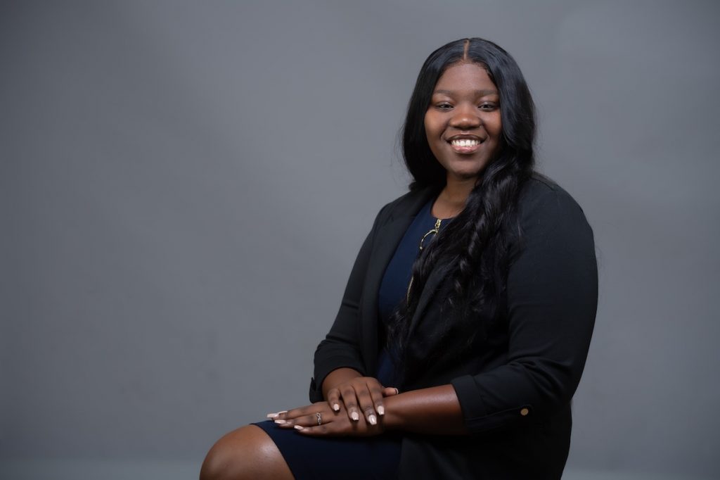 Moore sits in a black dress as she poses for a professional photo.