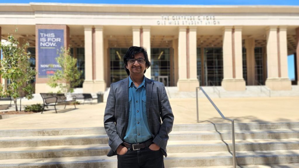 Khan stand in front of the steps leading up to the Student Union.