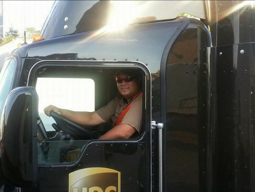 Billy Bailey sits in the cab of a brown UPS delivery truck.