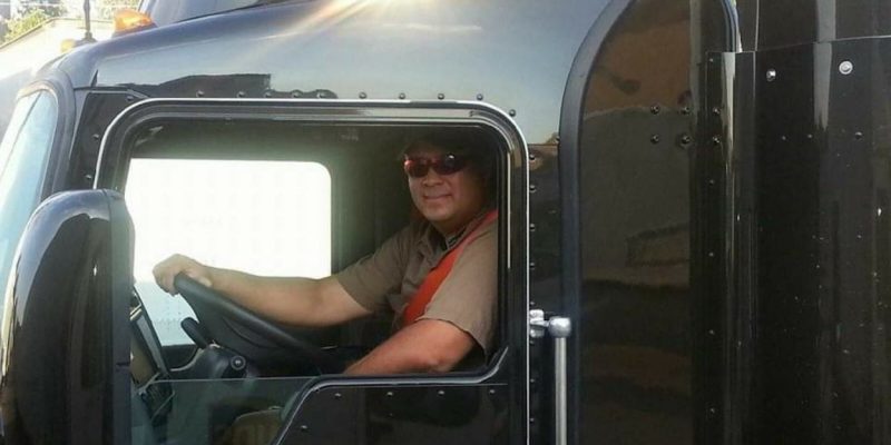 Billy Bailey sits in the cab of a brown UPS delivery truck.