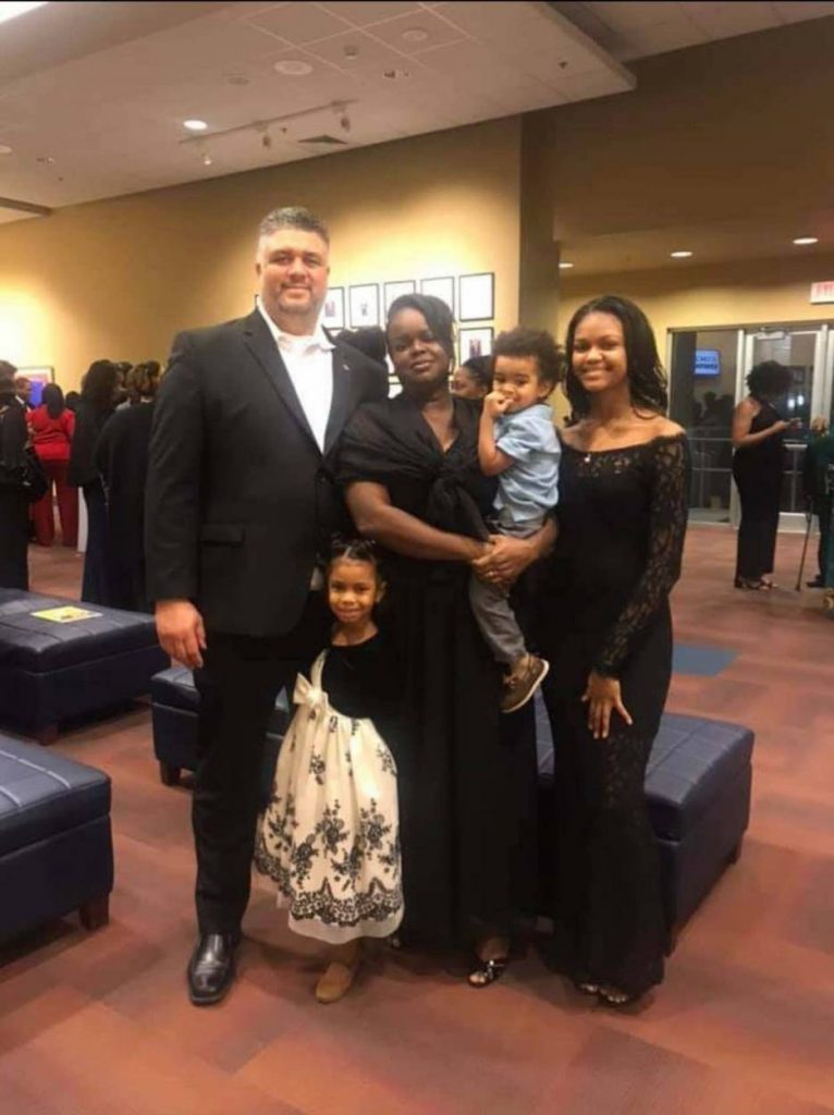 Bailey poses in a suit with his family around him.  
